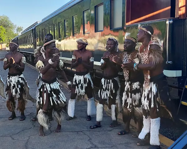 Danseurs traditionnels accueillant les voyageurs devant un train de luxe
