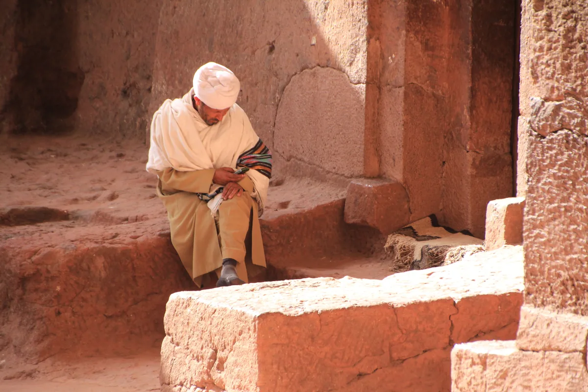 A man in traditional dress inside a rock-hewn church at Lalibela, Ethiopia