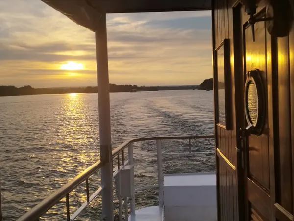 Coucher de soleil sur un fleuve, vu depuis la poupe d'un bateau