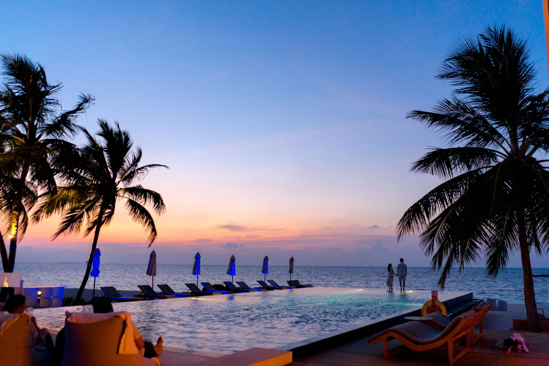 Travellers in the infinity pool of a luxury lodge at sunset