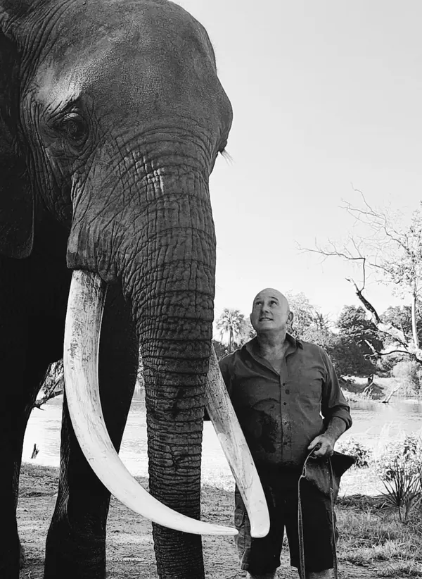 Patrick et un éléphant aux longues défenses, photographie verticale en N&B