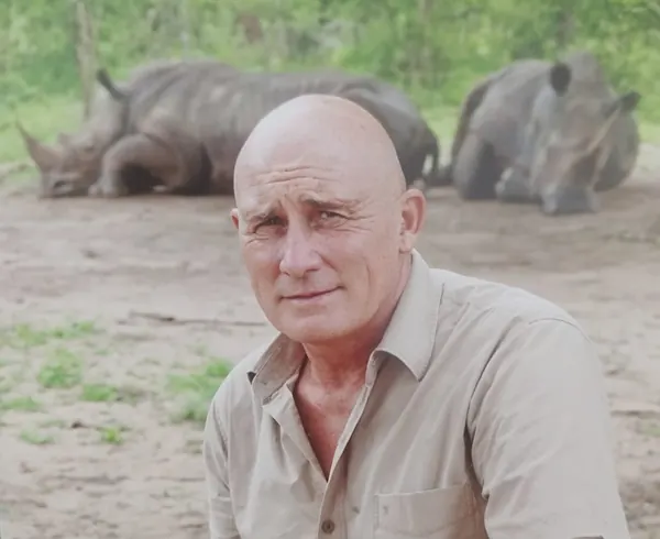 Patrick Plaetevoet, guide privé, devant deux rhinocéros couchés en réserve