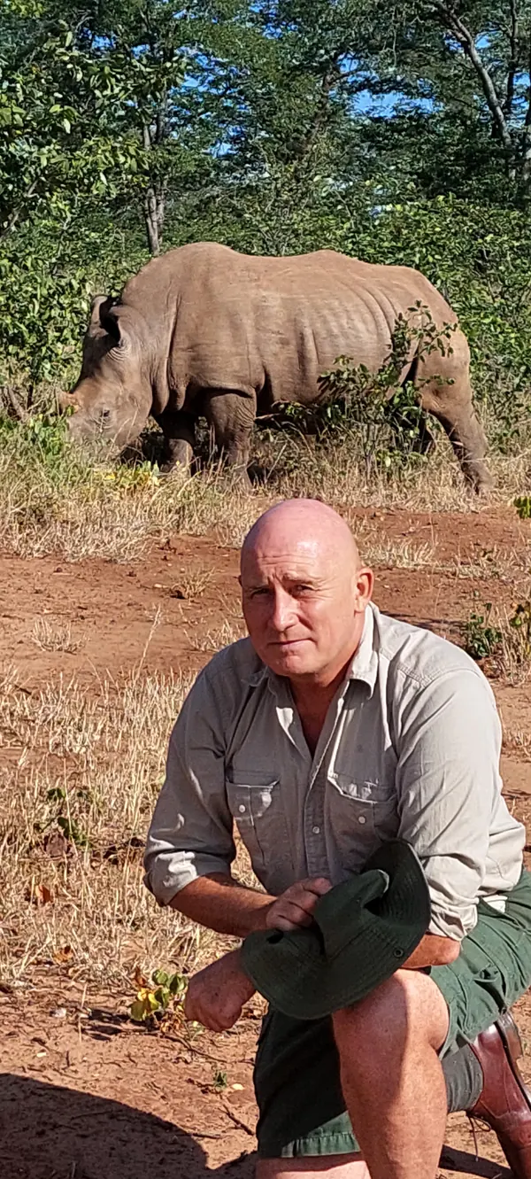 Patrick et un rhinocéros en brousse, photographie verticale