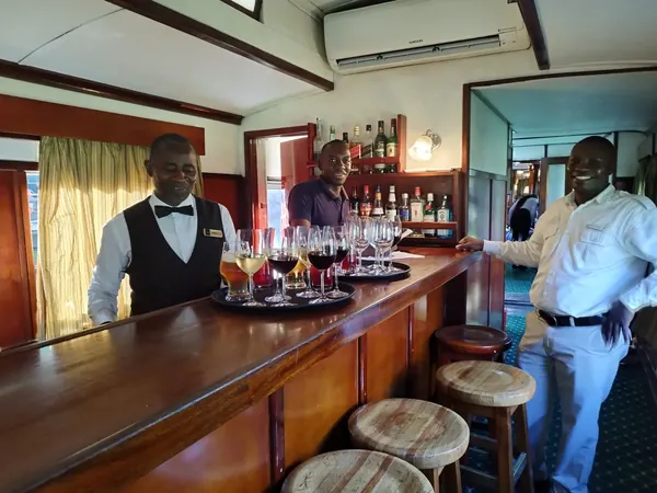 Bar en bois d'un train de luxe africain, personnel en livrée