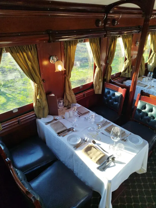 Wagon-restaurant en bois précieux, lumière dorée et table dressée