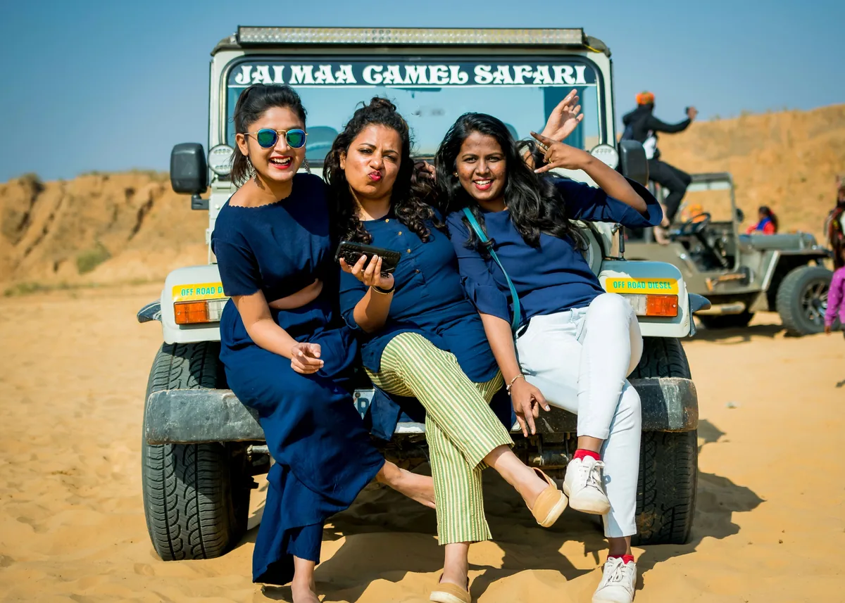 Three travellers together on a safari vehicle, beneath a clear sky