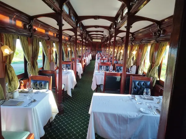 Wagon-restaurant en perspective, nappes blanches et boiseries