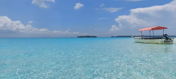 Petite barque à toit orange sur les eaux turquoise de Zanzibar